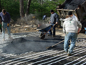 Applying hot asphalt over heat cable mats
