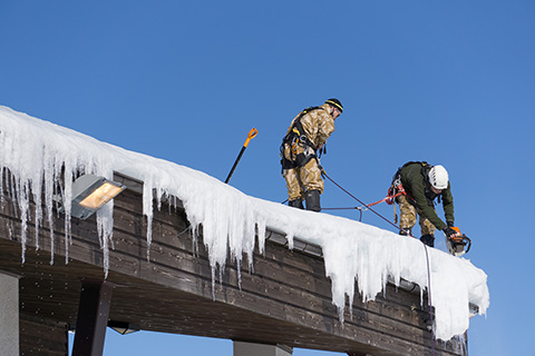 Removing the snow and icicles from a commercial roof.