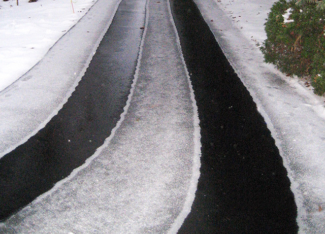 Heated tire tracks in asphalt driveway.