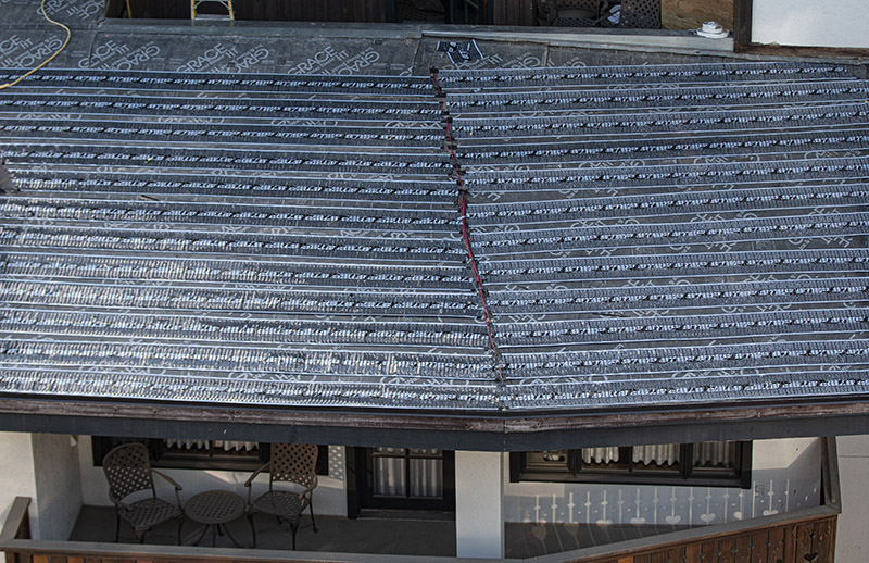 Low-voltage roof heating element being installed to heat resort hotel roof
