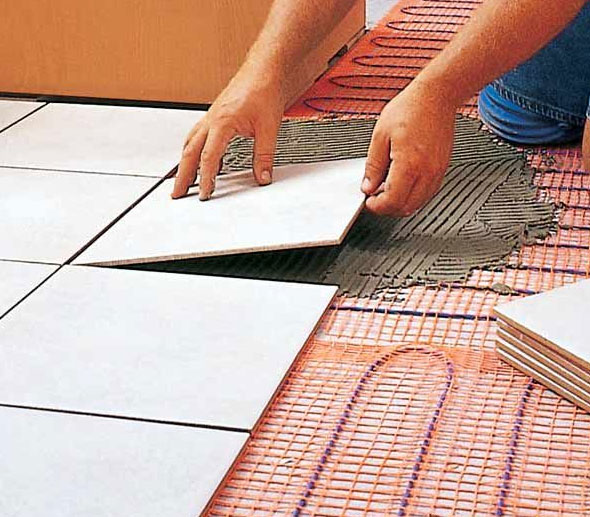 Tile being installed over floor heating cable and thinset