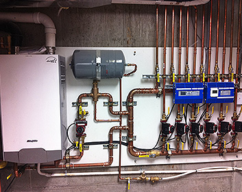 The mechanical room for a hydronic radiant heat system, showing boilers, controls and pumps.