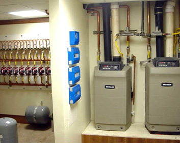 The mechanical room for a hydronic radiant heat system, showing boilers and pumps.